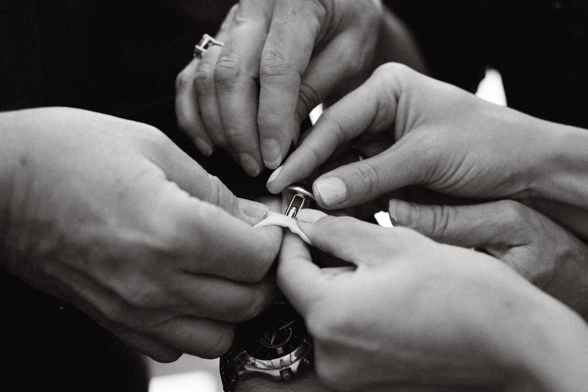 Close-up of hands fastening a cufflink before the ceremony, black and white